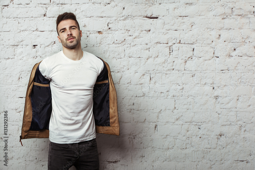 Handsome man in blank tshirt taking off his leather jacket, white