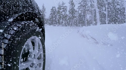 Winter. Road in the forest and lots of snow. Heavy snowfall and front tire of the car