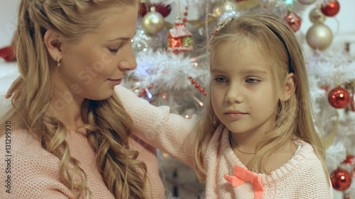 Mother hugs her little daughter in a Christmas atmosphere