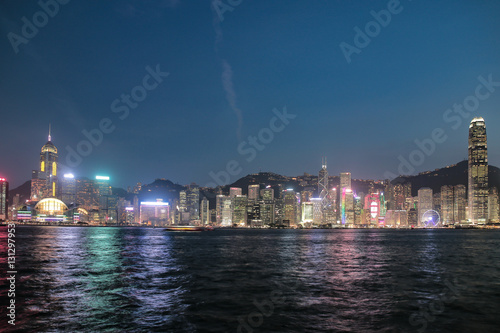 ​Hong Kong, China skyline panorama from across Victoria Harbor. Hong Kong city skyline view from harbor with skyscrapers buildings reflect in water at sunset