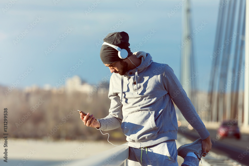 Fototapeta premium Man runner stretching legs before exercise run outdoors. Urban modern lifestyle healthy living concept.
