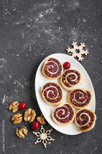 Cranberry nut swirl cookies on a white oval dish New Year's treats with nuts, cranberries, fir branches. Top view