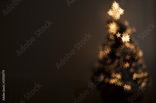 Christmas tree with fiber optic lights. Bokeh is star-shaped. Background for christmas card
