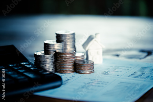 Row of coins with the house and calculator on the wooden table i