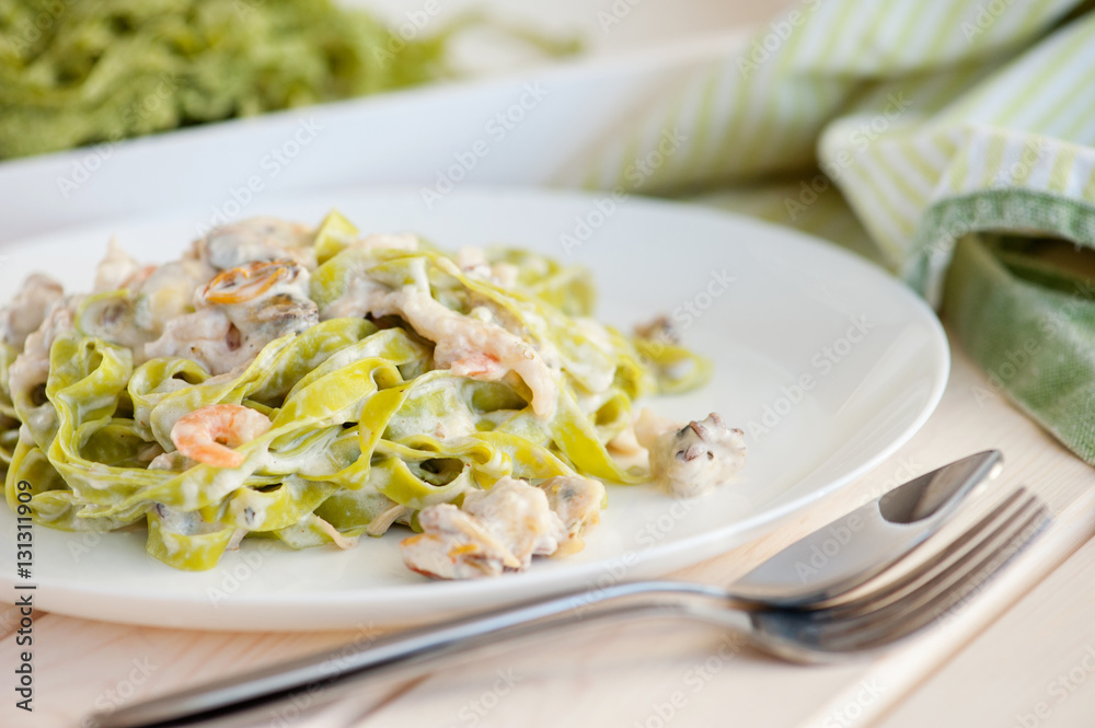 Sea foods and spinach fettuccine pasta on white dishes Sea foods and spinach fettuccine pasta on white dishes