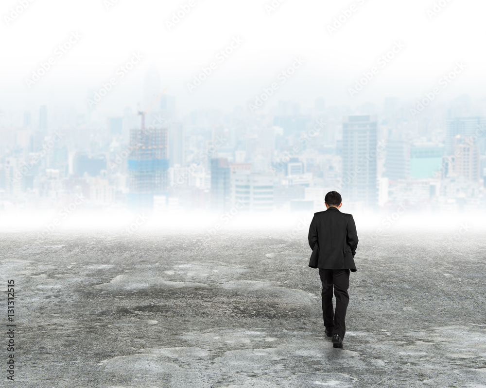 Man walking toward city buildings in mist Man walking toward city buildings in mist