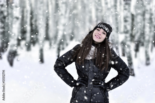 Girl with dark long hair in the winter park in snowfall