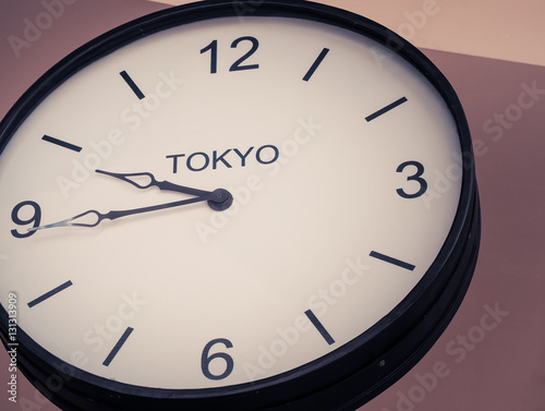 An airport clock showing Tokyo time zone at 9 past 45, Retro filter color