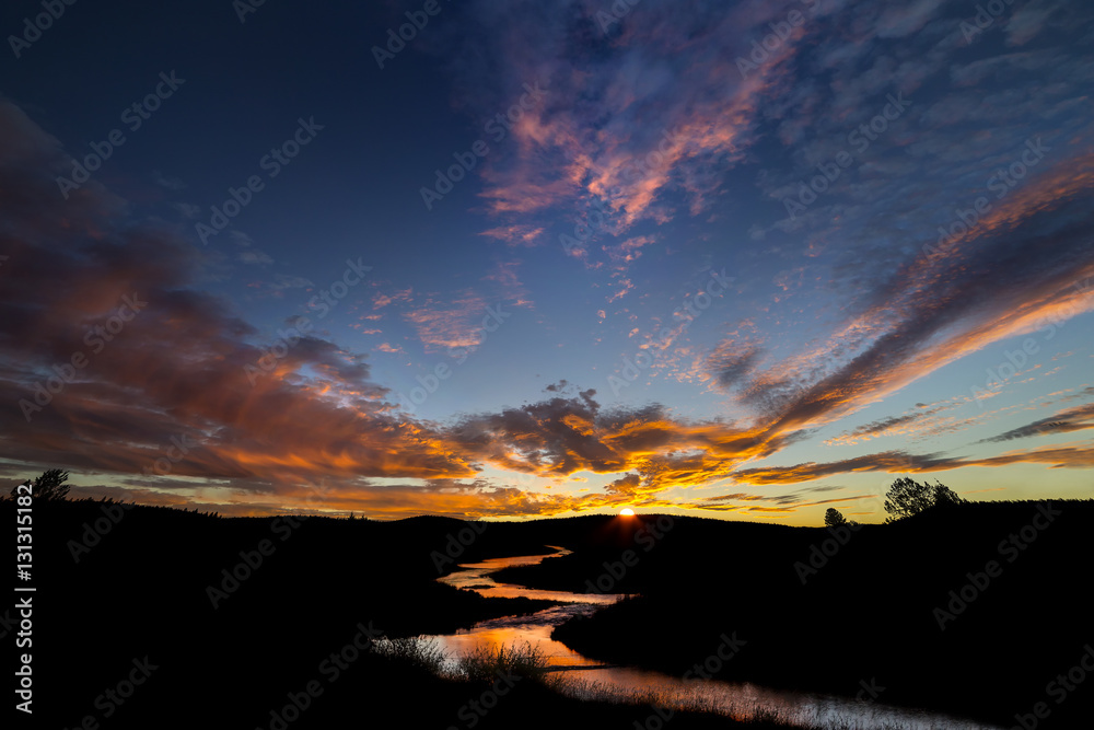 Sunset with winding river reflecting colorful sky.