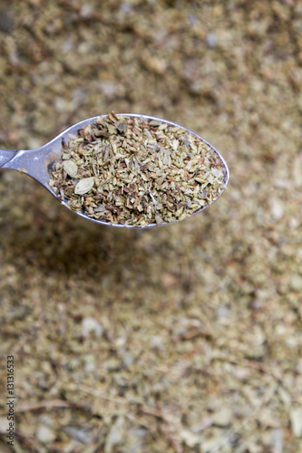 Dried oregano leaves in a spoon with shallow depth of field.