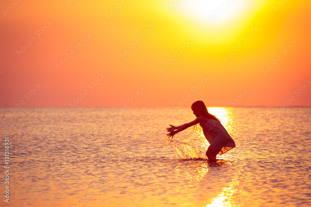child girl walking at the sunset sea