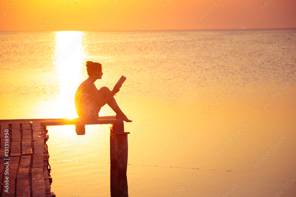 Fototapeta premium Dziewczyna czytająca na czas zachodu słońca