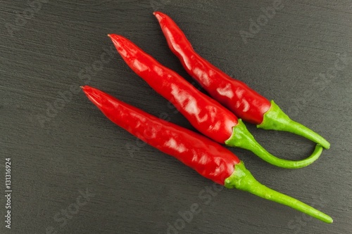 Red chilly pepper on wooden black background. Red hot chili peppers. Domestic cultivation extra hot chilli burn. Growing chili peppers. Spicy seasoning food. Healthy spices. 