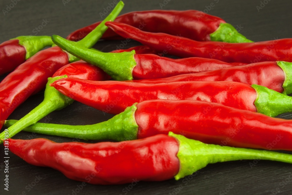 Red chilly pepper on wooden black background. Red hot chili peppers.  Domestic cultivation extra hot chilli burn. Growing chili peppers. Spicy seasoning food. Healthy spices.
