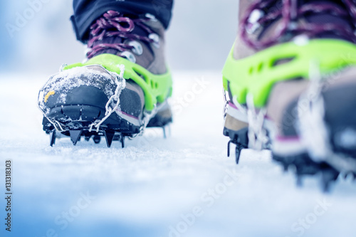 Hiking boots with equipment for ice. Snow like a background and sun. Sun is shining. Moutains and travel.