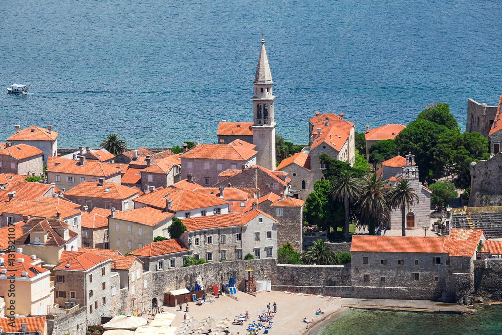 Bell tower of fortress of walled Old Town of Budva city. Aerial view with houses roofs. Adriatic sea. Montenegro