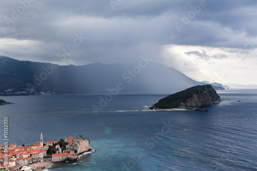 BUDVA, MONTENEGRO - CIRCA JUN, 2016: Rain is over Budvanska riviera and Sveti Nikola island in Adriatic sea. The medieval walled town is on peninsula. Montenegro, Europe photo