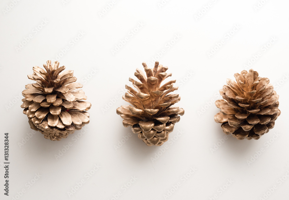 High angle view of three gold painted pine cones on white table High angle view of three gold painted pine cones on white table