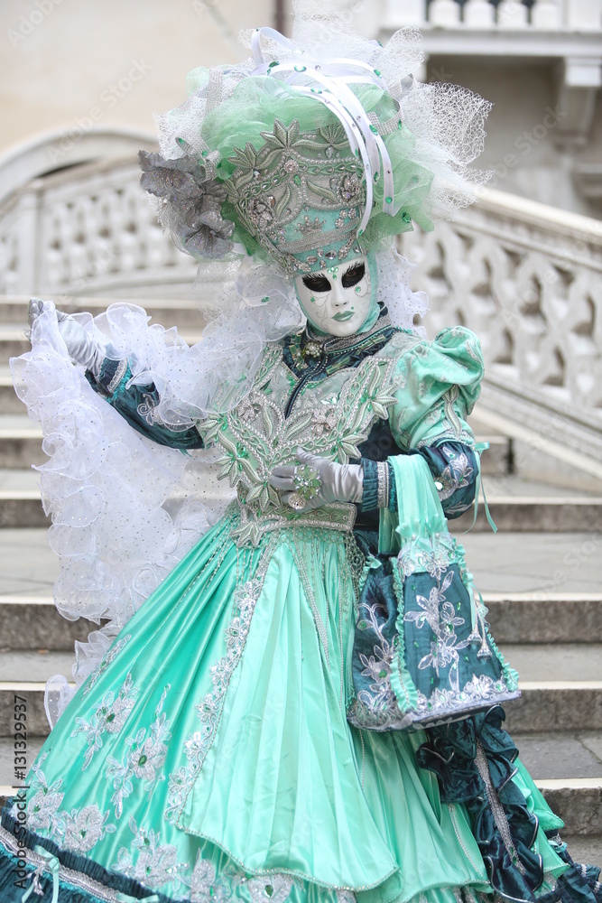Venice masked lady in green costume on stairs	