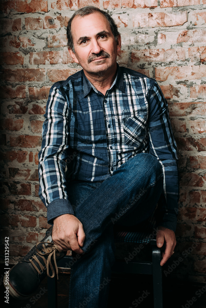 Handsome middle aged man is dressed in a casual clothing. Red brick wall background. Handsome middle aged man is dressed in a casual clothing. Red brick wall background.