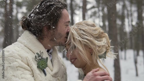 Outdoor winter forest shot of young wedding couple having fun under snowfall, 120FPS slowmotion
