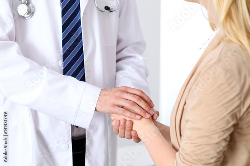 Hand of doctor reassuring her female patient. Medical ethics and trust concept