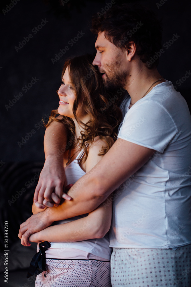 Happy couple of lovers in pajamas man embracing girl from behind. Happy couple of lovers in pajamas man embracing girl from behind.