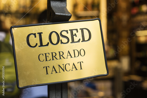 Photography Detail of golden closed sign, written in English, Spanish and Catalan