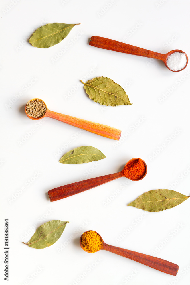 Naklejka premium spices in wooden spoons on white background top view
