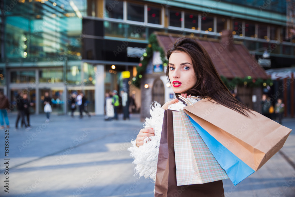 Fototapeta premium Portrait of beautiful young brunette woman with shopping bags outdoors