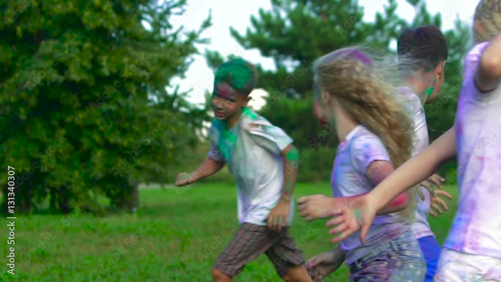 Group of children having fun in the park on a sunny warm day chasing each other to put some dye onto each other Group of children having fun in the park on a sunny warm day chasing each other to put some dye onto each other