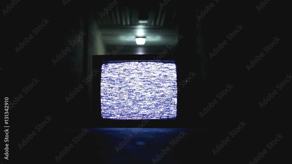 Tv sitting in hallway that is dark and a little scary.