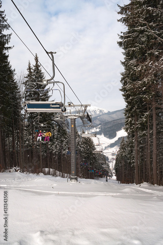 Happy skiers and snowboarders rising up on ski lift in the mountain winter resort © Fedoruk