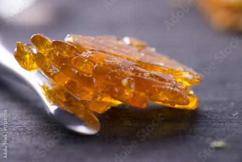 Piece of cannabis oil concentrate aka shatter with dabbing tool photo