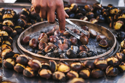 Man preparing roasted chestnuts, cooking outdoors. Street food i