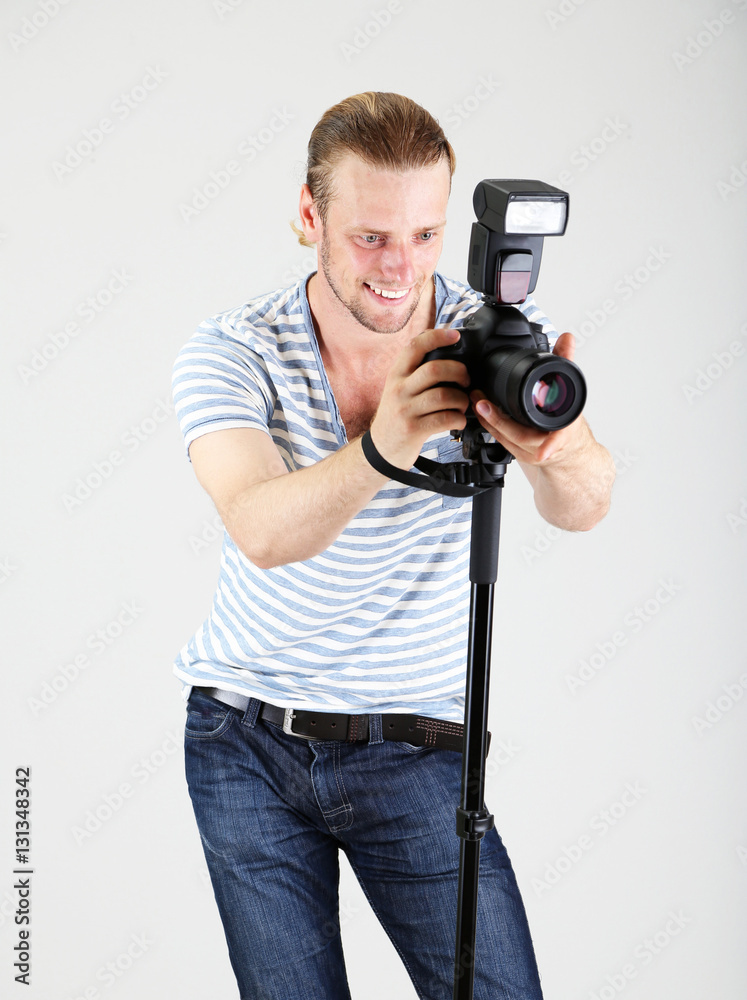 Handsome photographer with camera on monopod, on gray background Handsome photographer with camera on monopod, on gray background
