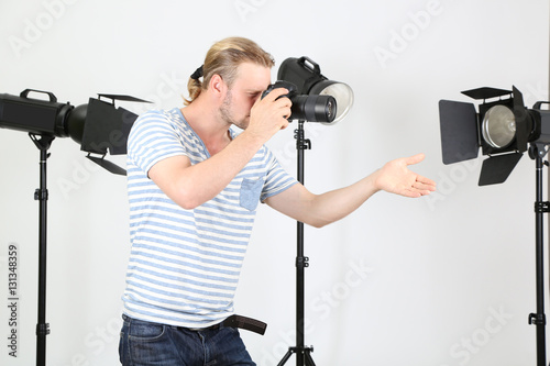 Handsome photographer with camera at working, on photo studio background