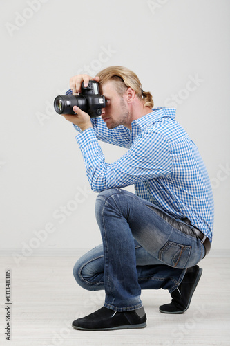 Handsome photographer with camera, on gray background