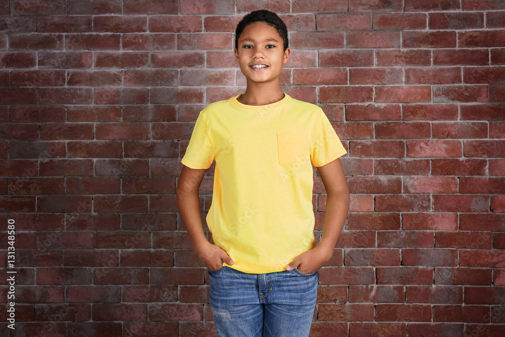 Young African American boy in blank yellow t-shirt standing against brick wall Young African American boy in blank yellow t-shirt standing against brick wall