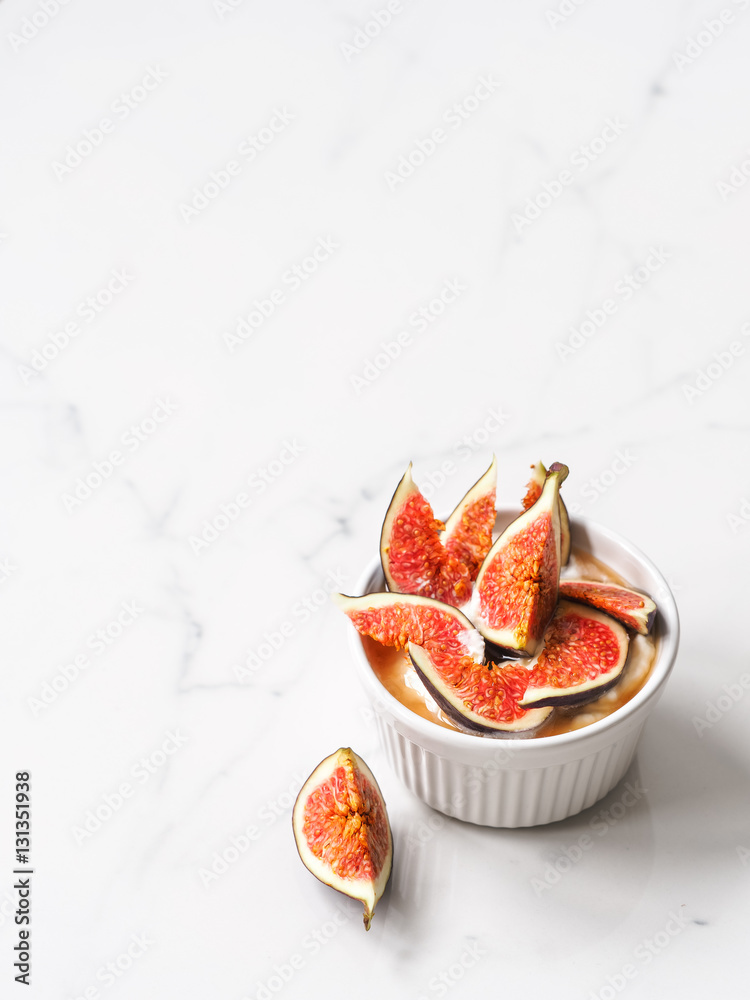 Yogurt with pieces of fig and honey in a white bowl on white background Yogurt with pieces of fig and honey in a white bowl on white background