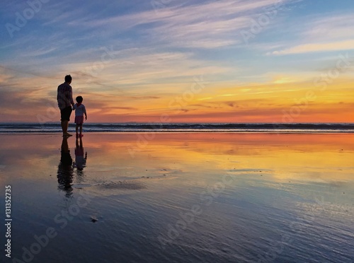 Silhouette of father and child at beach shoreline during sunset © samantoniophoto