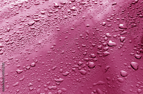 Rain drops on pink metal surface.