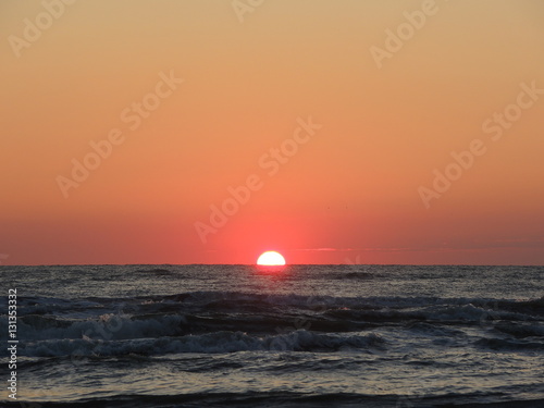 Fototapeta Naklejka Na Ścianę i Meble -  Fiery sunrise at Italian beach. Summer season. Emilia Romagna region. Adriatic sea. Italy