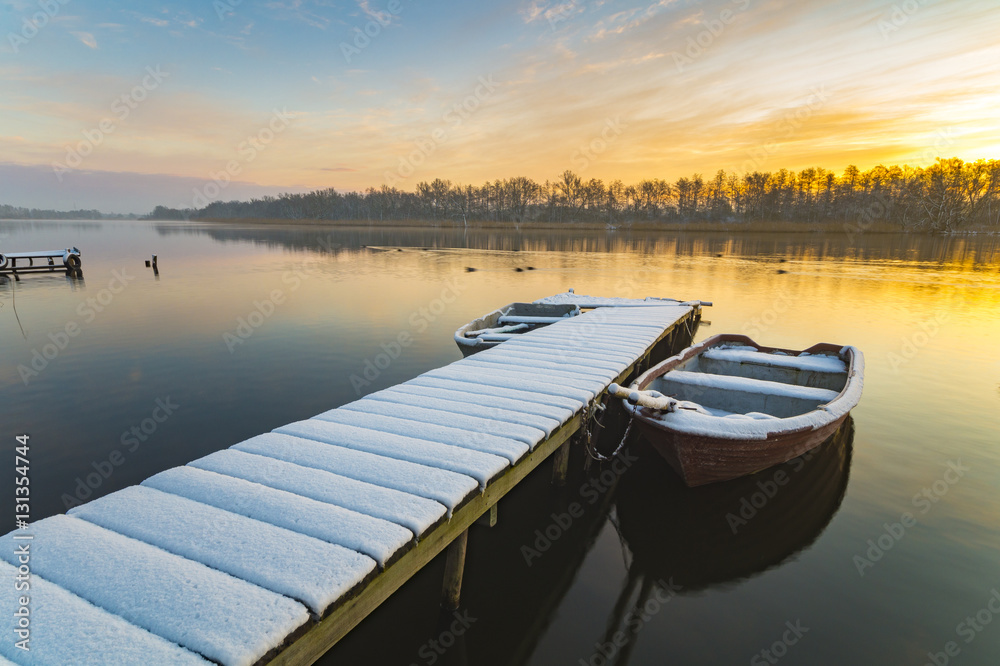 boat moored to the snow-covered bridge over the lake in winter m