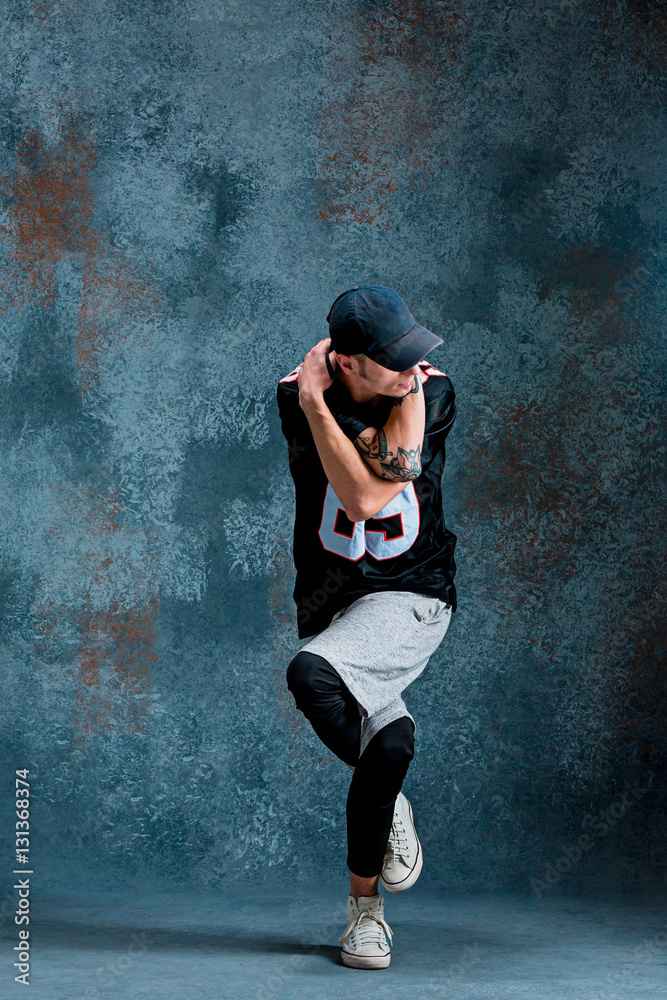Fototapeta premium Young man break dancing on wall background.