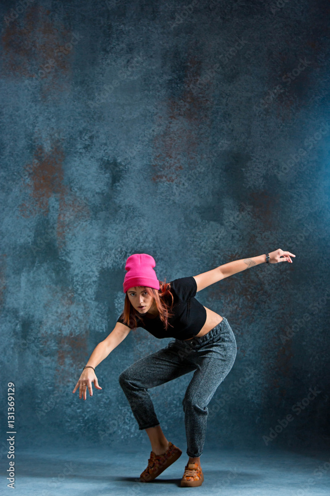 Young girl break dancing on wall background.