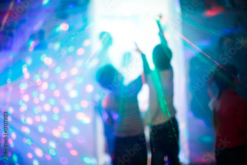 Children at a disco during the laser show with colorful rays lig