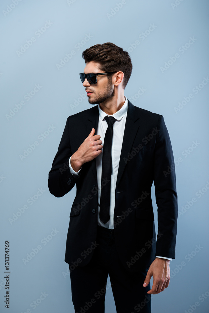 Young stylish businessman in black glasses touching suit Young stylish businessman in black glasses touching suit