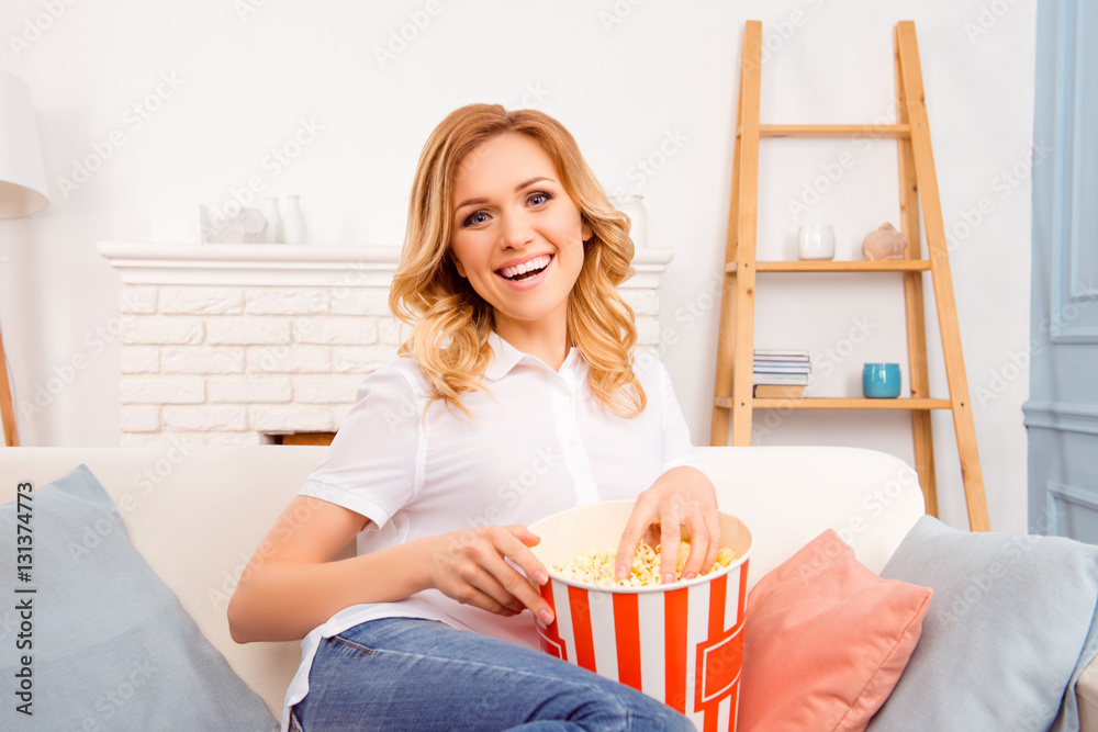 Laughing woman eating popcorn and watching interesting comedy