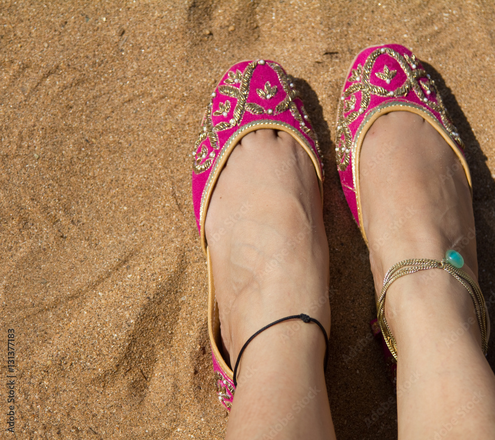 A lady wearing a pair of pink traditional Indian women's shoes (jutis) at  the Anjuna beach in north Goa, India Stock Photo | Adobe Stock